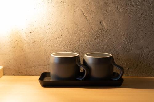 two coffee mugs sitting on a tray on a table at Yoichi LOOP in Kurokawamachi