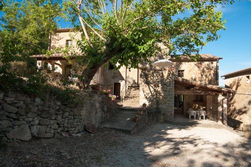 a stone house with two people sitting on chairs in front of it at Pilari Intera struttura in Corgna