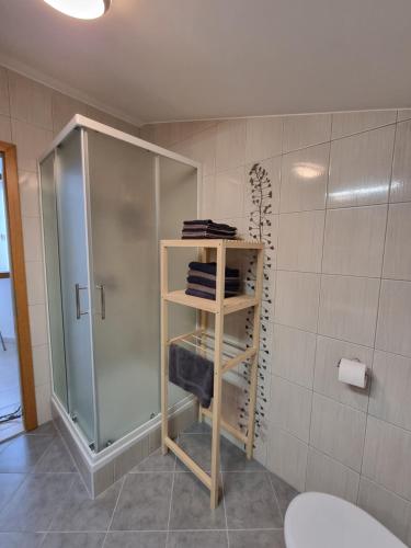 La salle de bains est pourvue d'une douche et d'une étagère avec des serviettes. dans l'établissement Forest View, 2-floor Apartment, à Hočko Pohorje