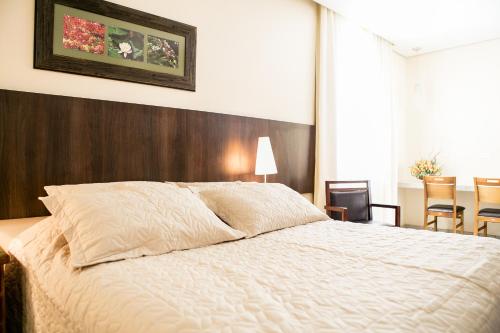 a bedroom with a large white bed with a wooden headboard at Pousada Sossego da Pampulha in Belo Horizonte