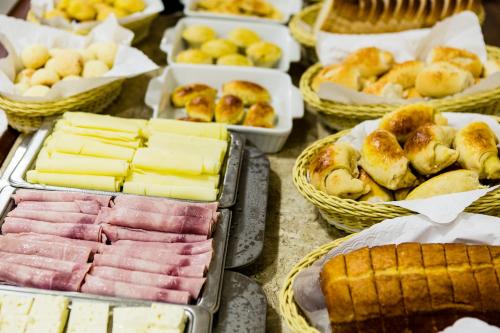 a table filled with different types of bread and pastries at Pousada Sossego da Pampulha in Belo Horizonte