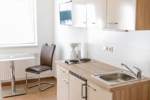 eine kleine Küche mit einer Spüle und einem Stuhl in der Unterkunft Weingut Guttmann - Apartment Schwalbennester in Weiden am See