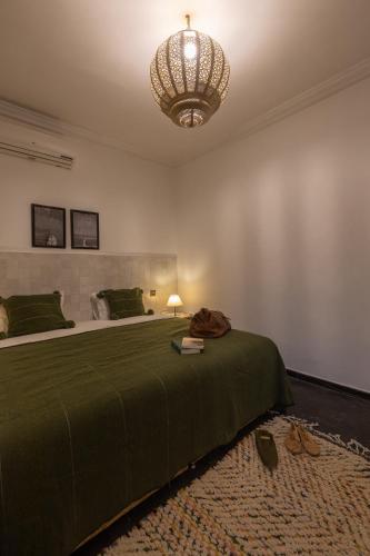 a bedroom with a green bed and a chandelier at Riad Ksar Saad & Spa in Marrakech