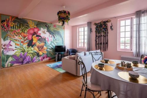 un salon avec une table et une grande fresque murale. dans l'établissement Le Rose poudré - Spacieux et lumineux- Hypercentre, à Lisle-sur-Tarn
