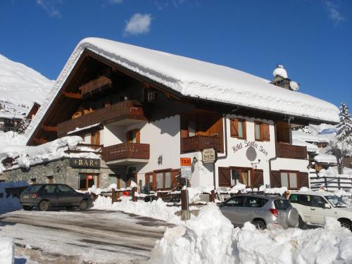 a snow covered building with cars parked outside of it at Santa San in Champoluc