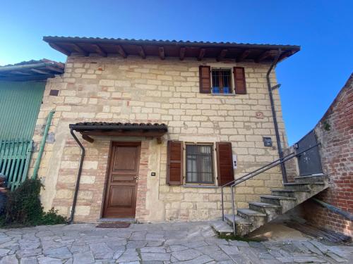 un pequeño edificio de ladrillo con puerta y escaleras en Casa Vistabella, en Frassinello Olivola