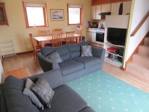 a living room with a couch and a dining room at Osprey, Longhouse Cottages in Rosemarkie