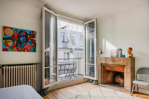 un salon avec une cheminée et une fenêtre dans l'établissement Courcelles Design Duplex, à Paris