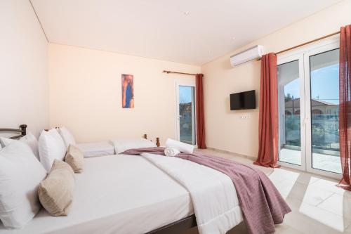 a white bedroom with a large bed and a window at Astarte Villas - Ocean Pool Villa in Tsilivi