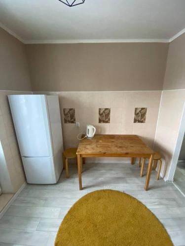eine Küche mit einem Holztisch und einem Kühlschrank in der Unterkunft Уютные апартаменты в центре города in Aqtöbe