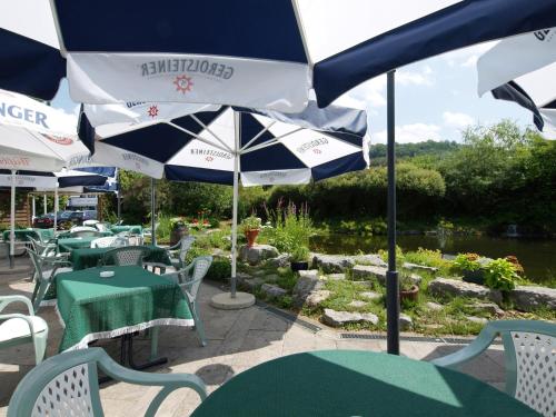 a patio with tables and chairs and an umbrella at H+ Hotel Stuttgart Herrenberg in Herrenberg