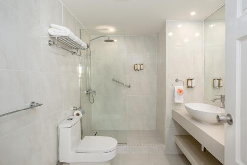 a white bathroom with a toilet and a sink at Sugar Bay Barbados - All Inclusive in Bridgetown
