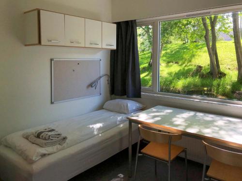 um quarto com uma cama, uma secretária e uma janela em Sund sommerhotell, Inderøy em Straumen