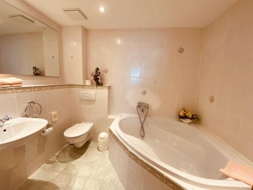 a bathroom with a tub and a toilet and a sink at Hotel Rotgiesserhaus in Kurort Oberwiesenthal