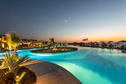 a large swimming pool at a resort at sunset at Astir Odysseus Kos Resort and Spa in Tigaki