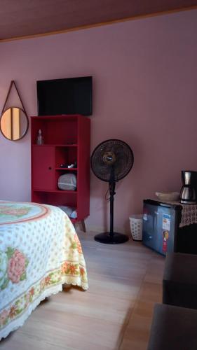 a bedroom with a bed and a flat screen tv at Chalés Mimar Lumiar Suítes individuais in Lumiar