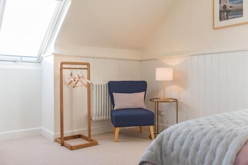 a bedroom with a blue chair and a mirror at Liberty Cottage in Broadstairs