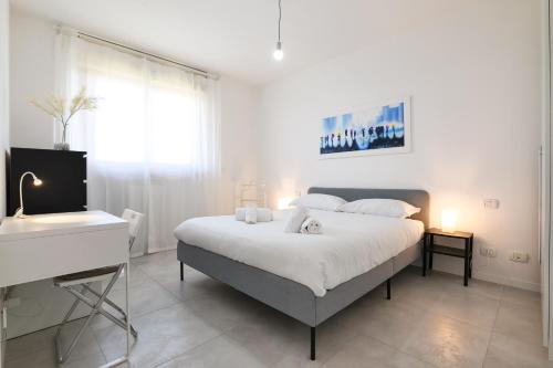 a white bedroom with a large bed and a desk at PrimoPiano - Caduti Missione in Milan