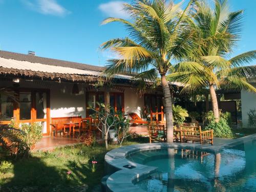 a house with a swimming pool and a palm tree at Khu Nghỉ Dưỡng Green Bungalow Phu Quoc in Phu Quoc