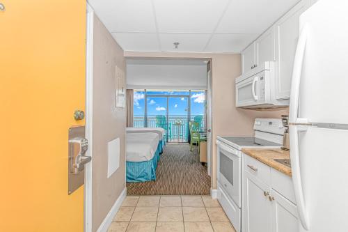 a kitchen with a room with a bed and a balcony at Caravelle 1512 in Myrtle Beach