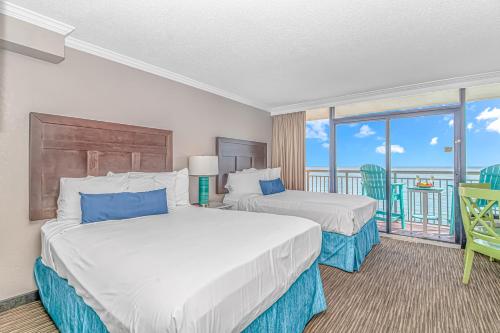 マートルビーチにあるCaravelle 1512のベッド2台とバルコニーが備わるホテルルームです。