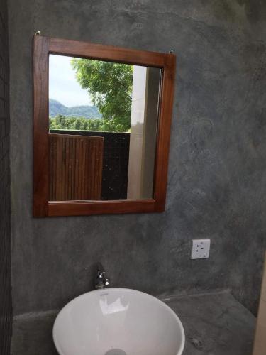 a bathroom with a sink and a mirror and a window at Takimi Mini Villa in Wellawaya