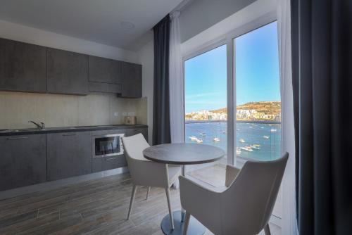 a kitchen with a table and chairs and a large window at Seaview Stays in St Paul's Bay