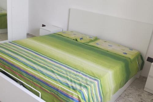 ein Bett mit einer bunten Decke darüber in der Unterkunft Casa Vacanze con giardino.LE CHICCHE in Maruggio