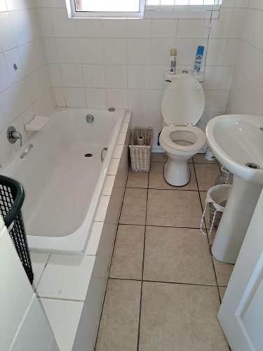 a bathroom with a tub and a toilet and a sink at Dadda's Place 2 in Port Shepstone