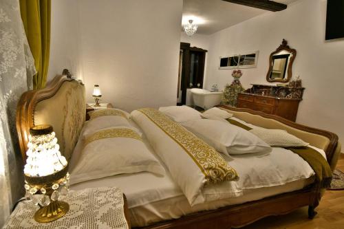 a bedroom with a bed with white and gold pillows at Casa Poveste Pensiunea-Muzeu in Câmpulung Moldovenesc