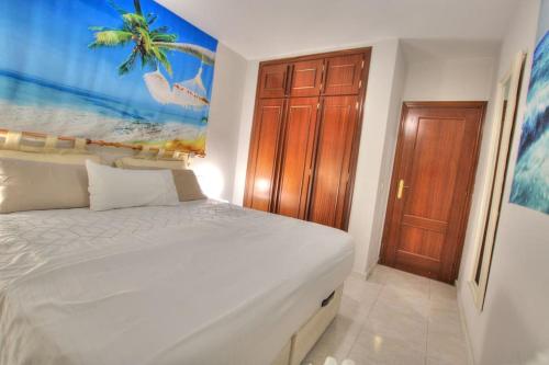 a bedroom with a white bed and a wooden door at Parque Playa, in the heart of La Cala de Mijas. in La Cala de Mijas