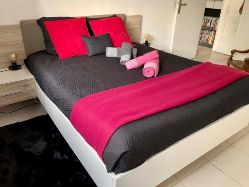 a large bed with red and black sheets and pink pillows at Key Largo villa 2p avec pkg clim grande terrasse avec jacuzzi proche port et plage in Bandol