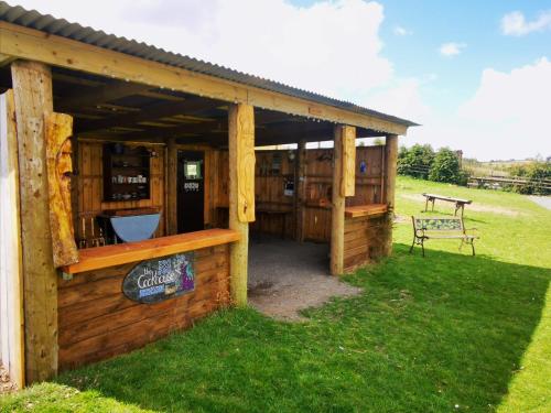 a wooden building with a bench in the grass at Bluebell in Newton Stewart