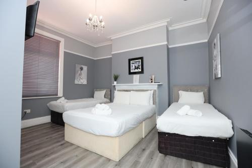 a bedroom with two beds with white sheets and a chandelier at Hotel Anfield in Liverpool
