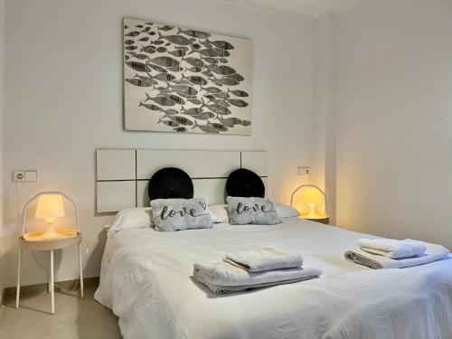 Un dormitorio blanco con una cama grande con toallas. en Apartamento Cala Ratjada. Recién reformado, en Cala Ratjada