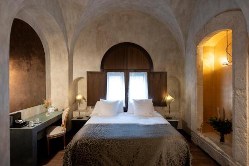 a bedroom with a bed and a table and a window at Hospes Palacio del Bailio, a Member of Design Hotels in Córdoba
