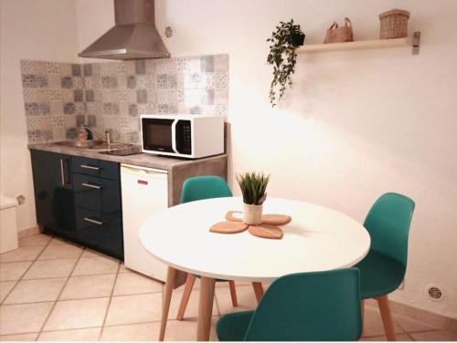 uma cozinha com uma mesa branca e cadeiras verdes em Appartement indépendant, Hyper-centre pittoresque em Salon-de-Provence