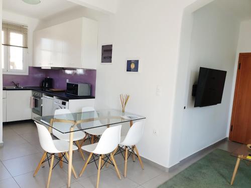 a kitchen with a glass table and white chairs at KYMA Apartments - Athens Acropolis 4 in Athens