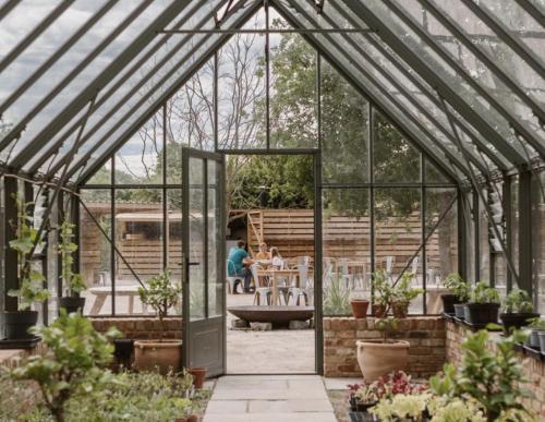 a greenhouse with a person sitting at a table in it at The Quaives - Cottages & Glamping in Canterbury