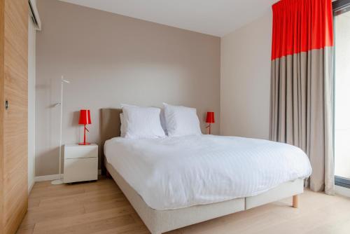 une chambre avec un lit blanc et un rideau rouge dans l'établissement Casteja Modern Residence, à Boulogne-Billancourt