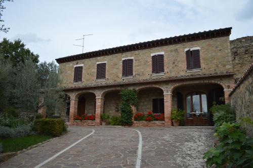 a large brick building with red flowers in front of it at B&B Daria - Deb'S Monticchiello in Monticchiello