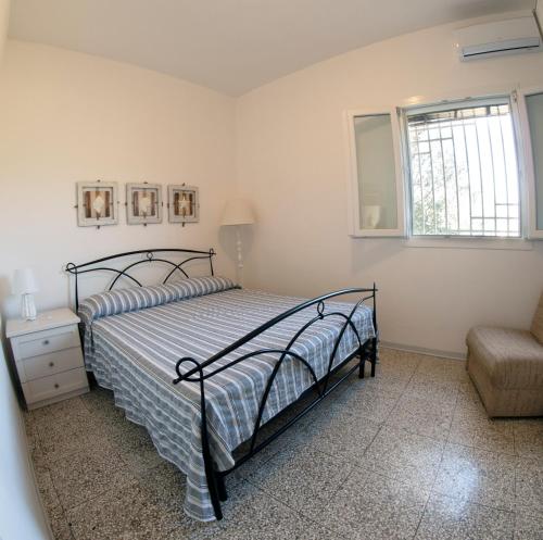 a bedroom with a bed and a chair and a window at Casa tu Nonnu in Ugento