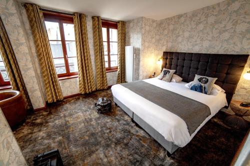 a bedroom with a large bed and windows at Logis Hôtel & Restaurant - Les Hauts de Montreuil in Montreuil-sur-Mer