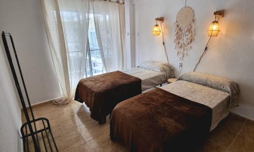 a hotel room with three beds and a window at Piso Vintage Centro Gandía in Gandía