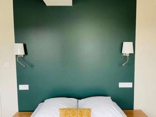a bedroom with a green wall with a bed and two lamps at Restaurant Hotel Logis Chez Sophie in Briouze