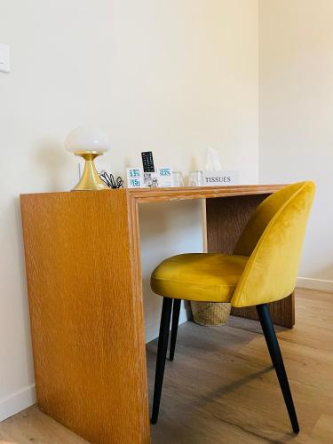 a yellow chair sitting next to a wooden desk at Restaurant Hotel Logis Chez Sophie in Briouze