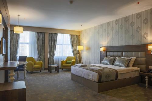 a hotel room with a bed and a desk and chairs at Royal Hotel Inegol in Inegol