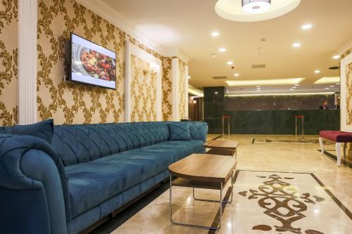 a living room with a blue couch and a tv at Royal Hotel Inegol in Inegol