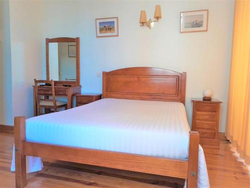 a bedroom with a wooden bed and a mirror at Hotel Alianca in Figueira da Foz