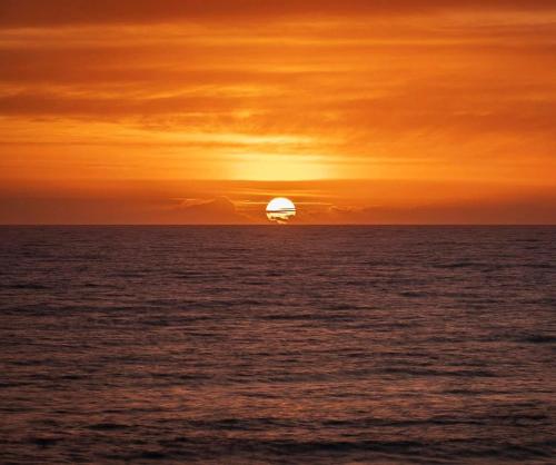 a sunset over the ocean with a ship in the distance at Beachhouse La Palma in Costa Calma